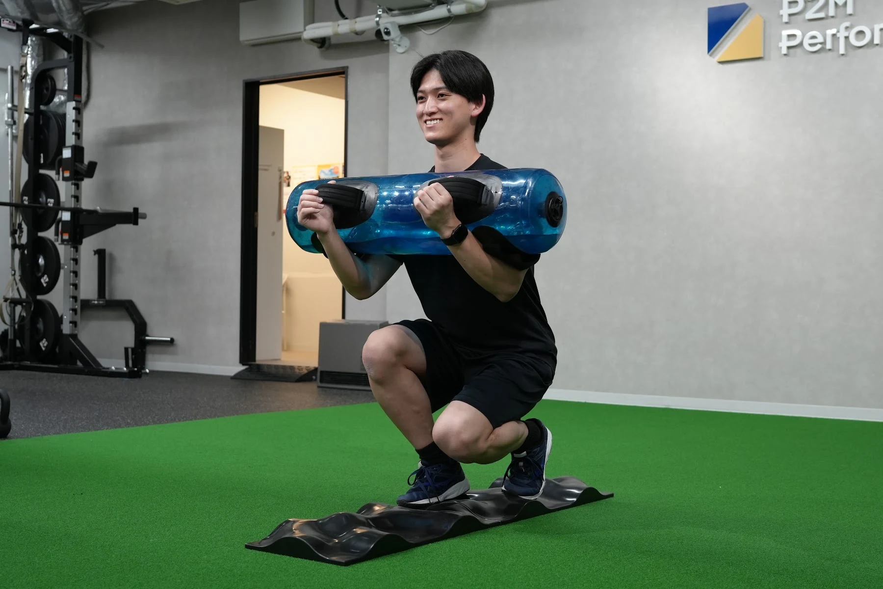 トレーニングツールを使ってスクワットする利用者